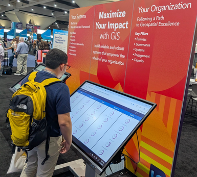 a UC attendee checking out the Geospatial Framework Assessment Dashboard at the Expo