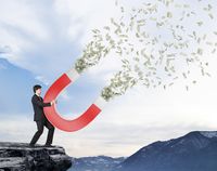 A person holding a magnet that attracts money. Unfortunately, the real world forces us to confront budgetary constraints.