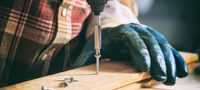 A person drilling a screw into wood.